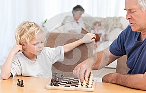 Young boy playing chess with his grandfather