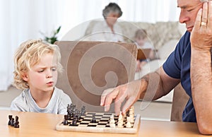 Young boy playing chess with his grandfather