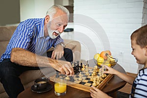 Young boy is playing chess with his grandfather
