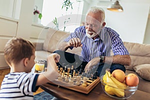 Young boy is playing chess with his grandfather