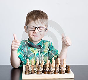 Young boy playing chess, showing thumbs up