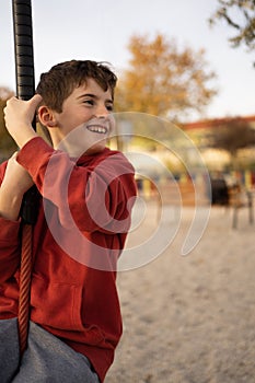 Young boy playing and having fun doing activities outdoors. Happiness and happy childhood concept. Kid swing on rope