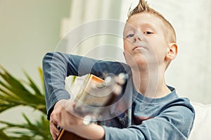 Young boy playing his guitar for the camera