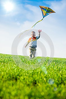 Young boy playing with his kite in a green field