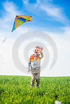 Young boy playing with his kite in a green field