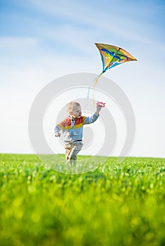 Young boy playing with his kite in a green field