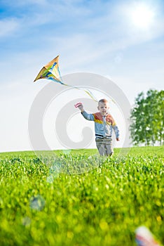 Young boy playing with his kite in a green field.