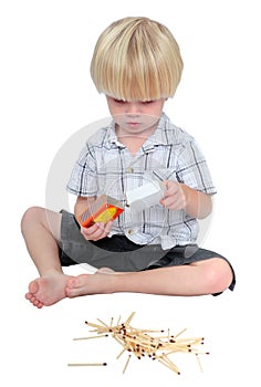 Young boy playing with matches on a white background