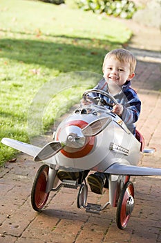 Young boy playing outdoors in airplane smiling