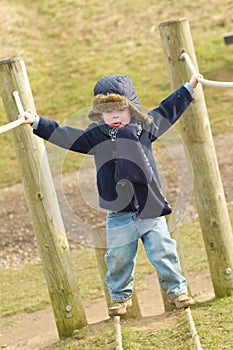 young boy playing at the park on a cold day