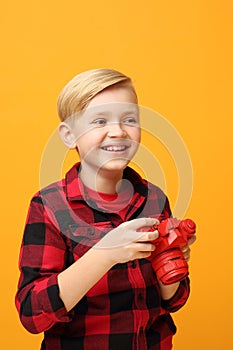 A young boy playing with a red camera.