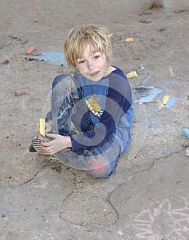 Young boy playing with sidewalk chalk