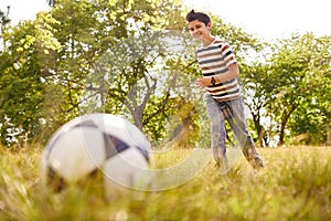 Young boy playing soccer game hitting ball