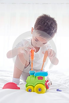 Young boy playing toys on bed