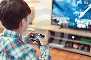 Young boy playing video game on console by controller