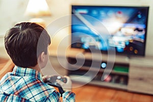 Young boy playing video game on console by controller