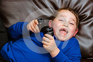 Young boy playing video game laying on couch