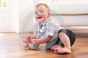 Young Boy Playing With Wooden Toy Car At Home