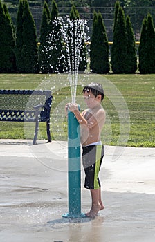 Young boy plays in a city play fountain