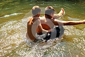 A young boy plays with his older brother in the wate