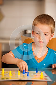 Young boy plays ludo game on a table in livingroom