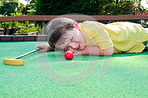 Young boy plays mini golf