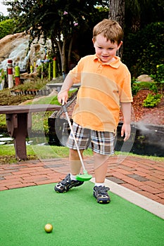 Young boy plays mini golf