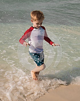 Young boy plays at the surf at the edge of the beach
