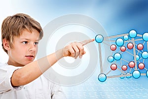 Young boy pointing at 3D molecules.