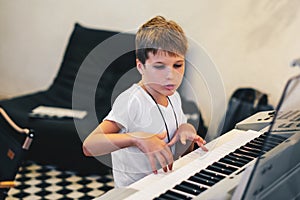 Young boy Portrait sitting at digital piano Playing keyboard focused kid activity indoors press on Key learning to play