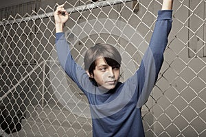 Young boy posing on a chain-link fence