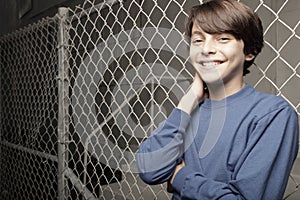 Young boy posing on a chain-link fence