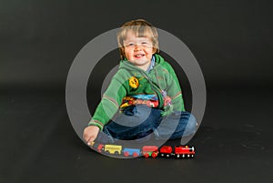 Young boy posing with a colorful toy train
