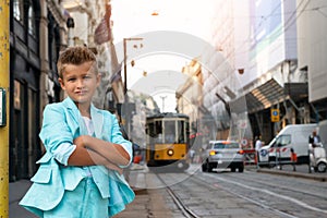 Young boy posing in the milanese street with old tram on background. Cute happy 6 years old boy posing in Milan, Italy. Kid`s