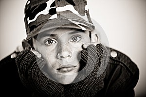 Young boy pouting while holding face in gloves