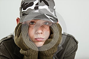 Young boy pouting while holding face in gloves