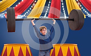 Young boy pretending to be strongman circus performer lifting big barbell