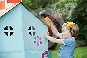 Young Boy Pretending To Fix Cardboard Playhouse