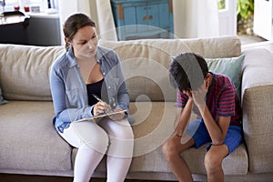 Young Boy With Problems Talking With Counselor At Home