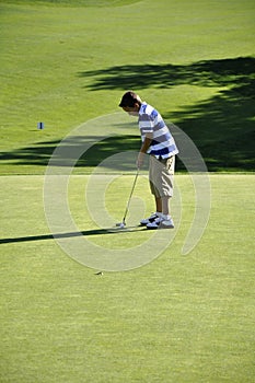 Young boy putting on golf course