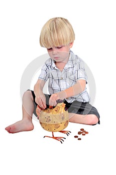 Young boy putting money into a piggy bank