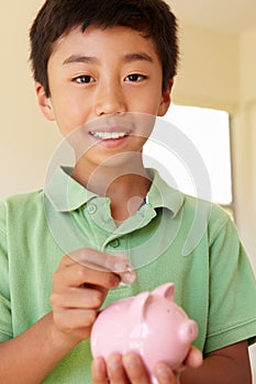 Young boy putting money in piggybank photo