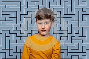 Young boy  with a puzzled expression against blue background blue background with drawing labyrinth