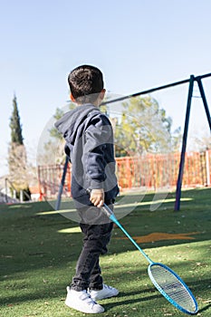 Young Boy With Racket In Park.