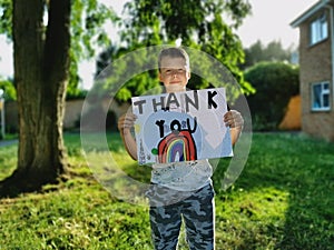 Young Boy with rainbow drawing and Thank You message for medical staff working through the Covid-19 Pandemic