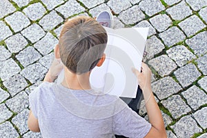 Young boy reading book outdoors