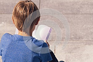 Young boy reading book outdoors