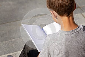 Young boy reading book outdoors