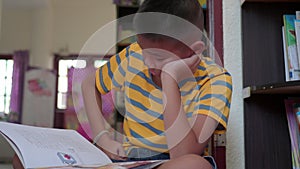 Young boy reading a book sitting on the floor.