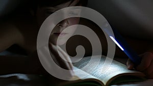 Young boy reading an interesting book at night